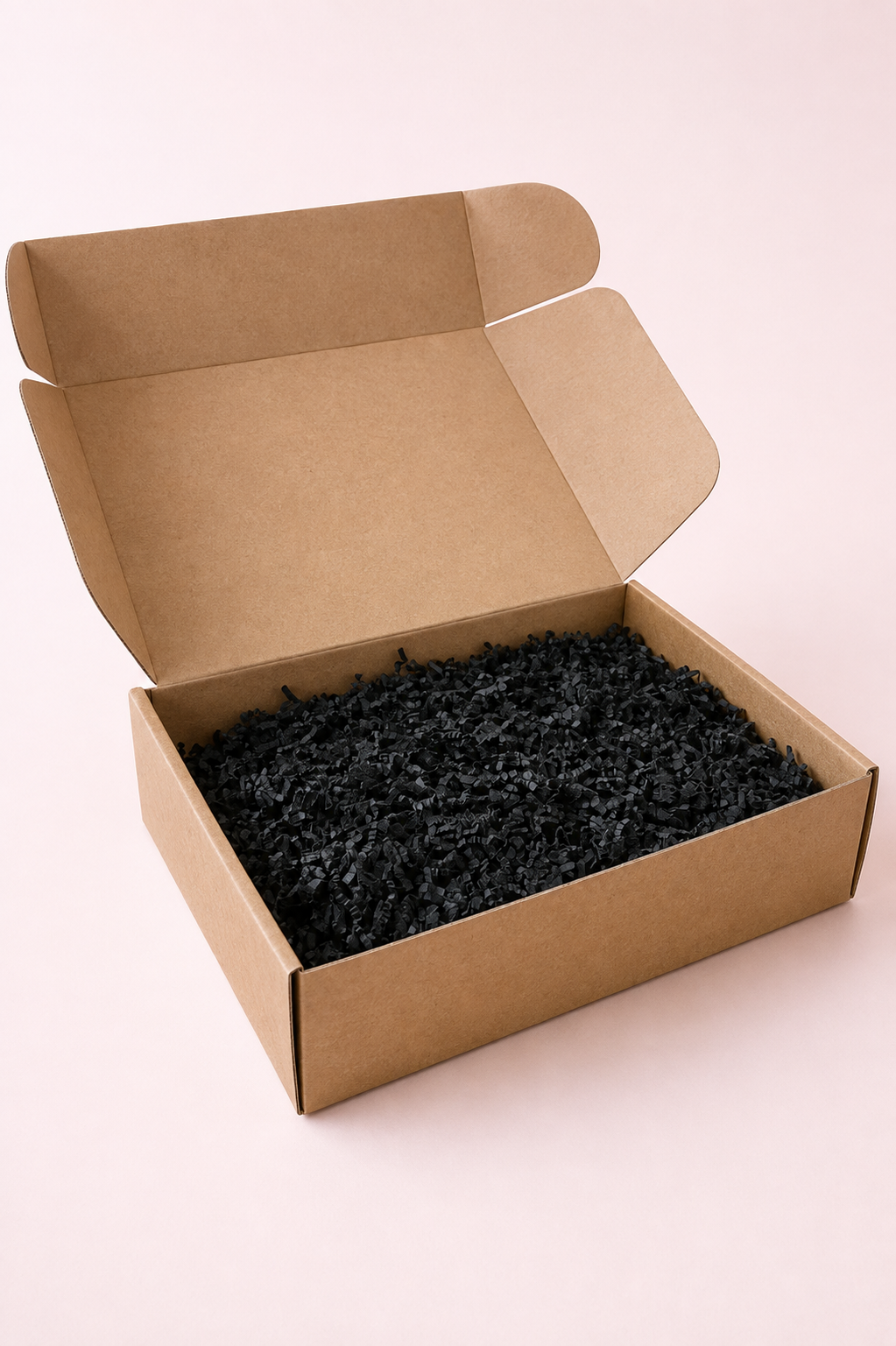 Naturel bruine kartonnen cadeaudoos met zwart opvulmateriaal, ideaal als luxe geschenkdoos om zelf te vullen.