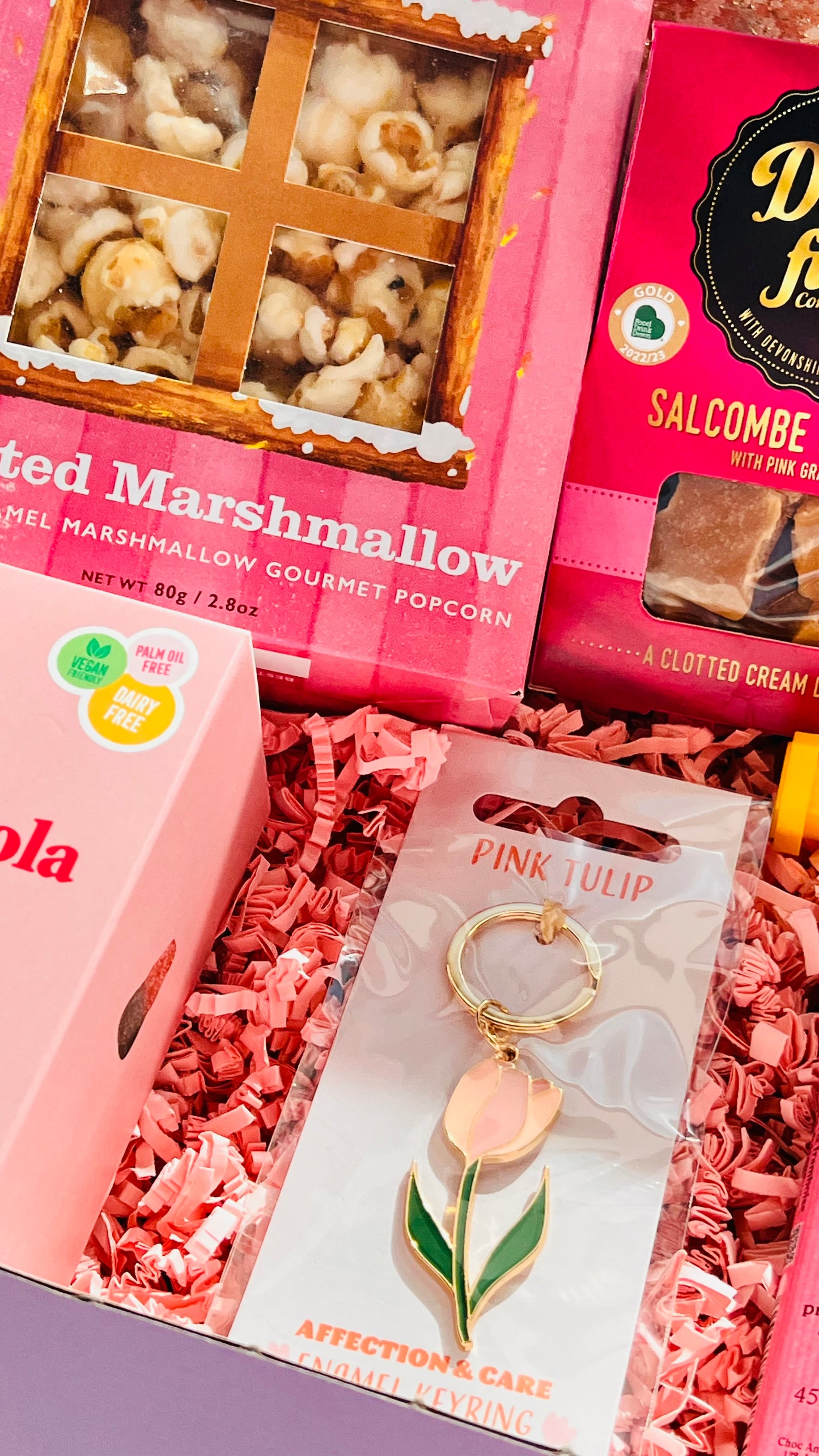Close-up van 12-delige roze cadeaubox met snoep, koekmix en lifestyle items – lente cadeau box voor haar
