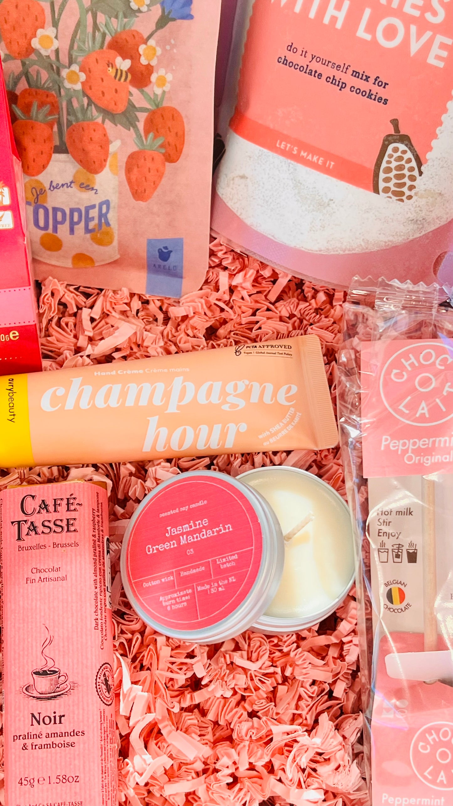 Detailfoto van handcrème, geurkaars en roze accessoires in luxe cadeaubox – selfcare cadeau voor haar

