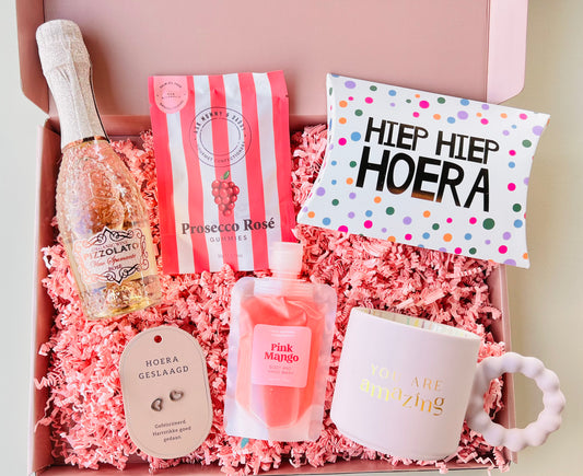 Luxe Geslaagd Cadeaubox met You Are Amazing mok, mini Pizzolato Rosé Prosecco, fruit gummies, Hiep Hiep Hoera toffees, Pink Mango shower en bath gel, geslaagd oorbellen en persoonlijke cadeaukaart, feestelijk verpakt als origineel diploma cadeau.