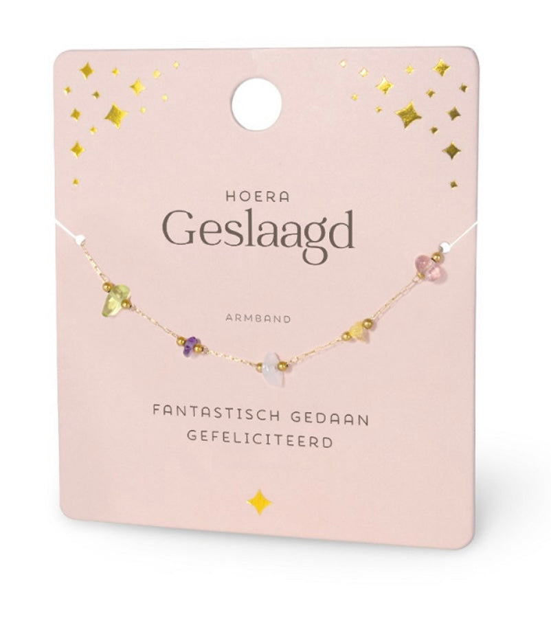 Lichtroze ‘Hoera Geslaagd’ cadeaukaart met verfijnd goudkleurig armbandje en kleurrijke edelsteentjes. Stijlvol geslaagd cadeau voor diploma of examen