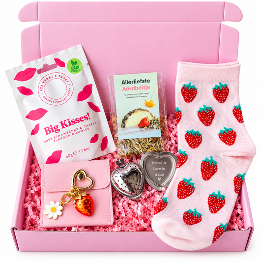 Roze cadeaubox met aardbeiensokken, aardbeienthee, aardbeiensnoepjes, roze portemonneetje met sleutelhanger en hartvormig theezeefje.