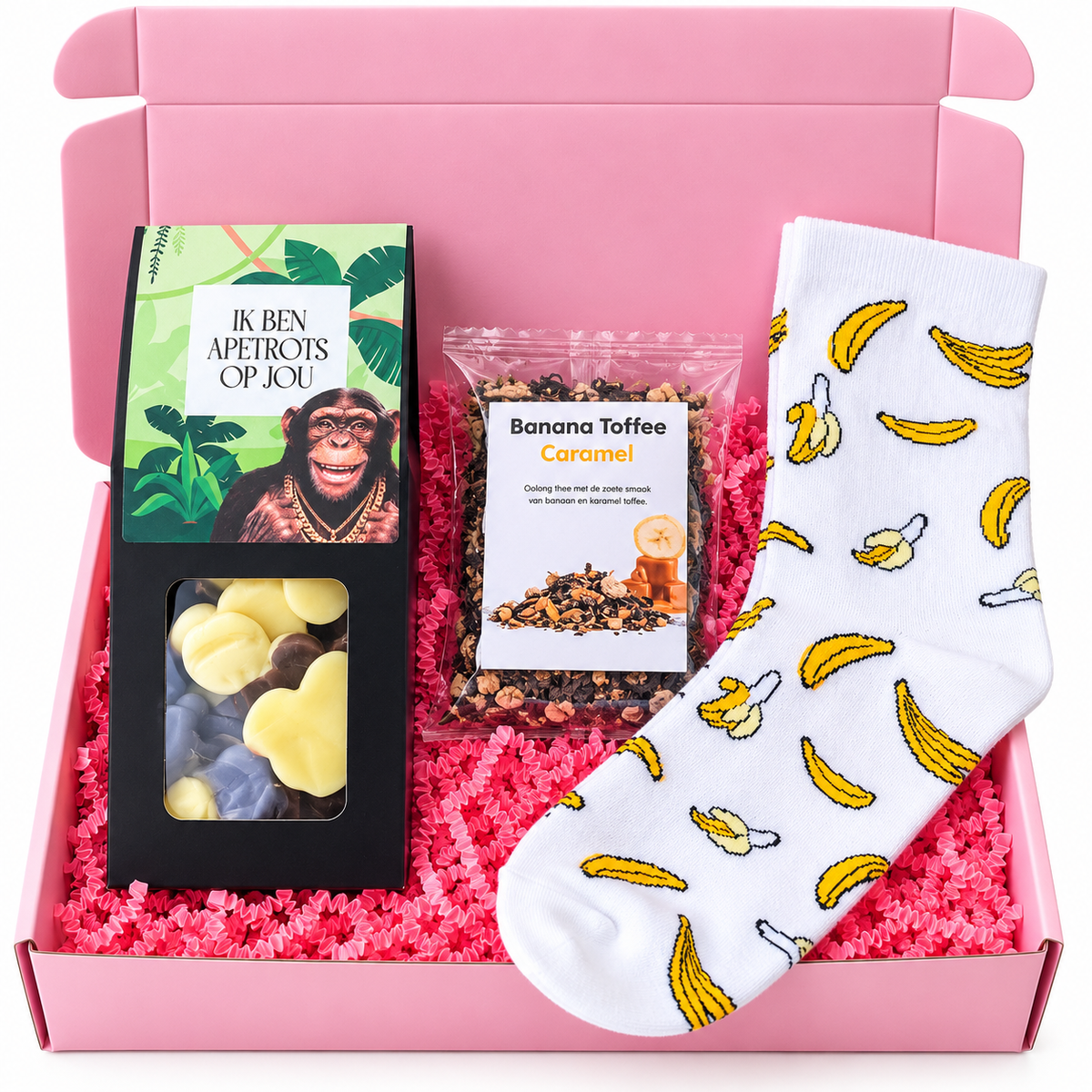 Roze cadeaubox met witte bananensokken, Banana Toffee Caramel thee en chocolade in de vorm van apen, gevuld met roze papiersnippers