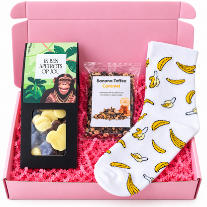 Roze cadeaubox met witte bananensokken, Banana Toffee Caramel thee en chocolade in de vorm van apen, gevuld met roze papiersnippers