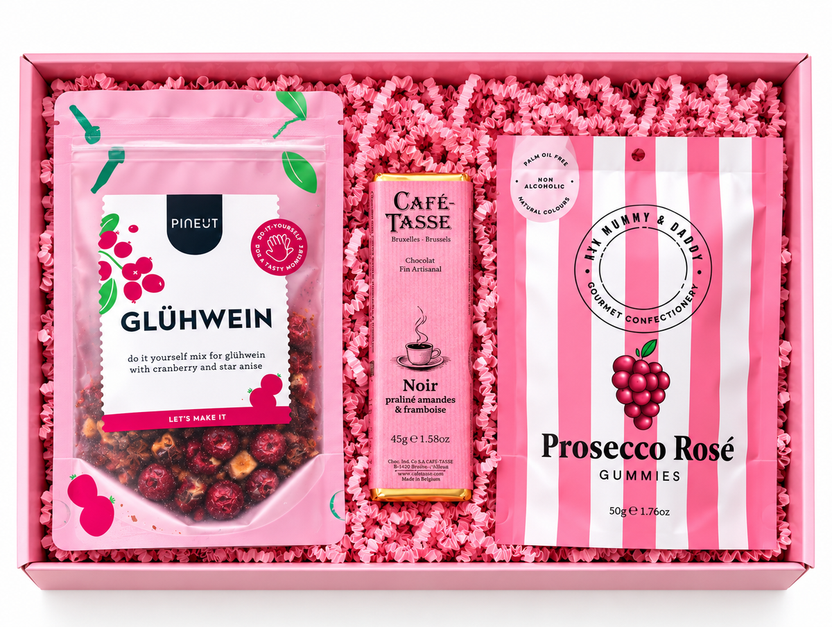 Roze cadeaubox met Glühwein mix, Café-Tasse chocolade en Prosecco Rosé gummies op een witte achtergrond
