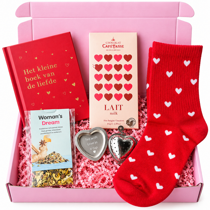 Roze cadeaubox met rode sokken met witte hartjes, het boek Het kleine boek van de liefde, Café-Tasse melkchocolade, Woman’s Dream kruidenthee en een hartvormig theezeefje.