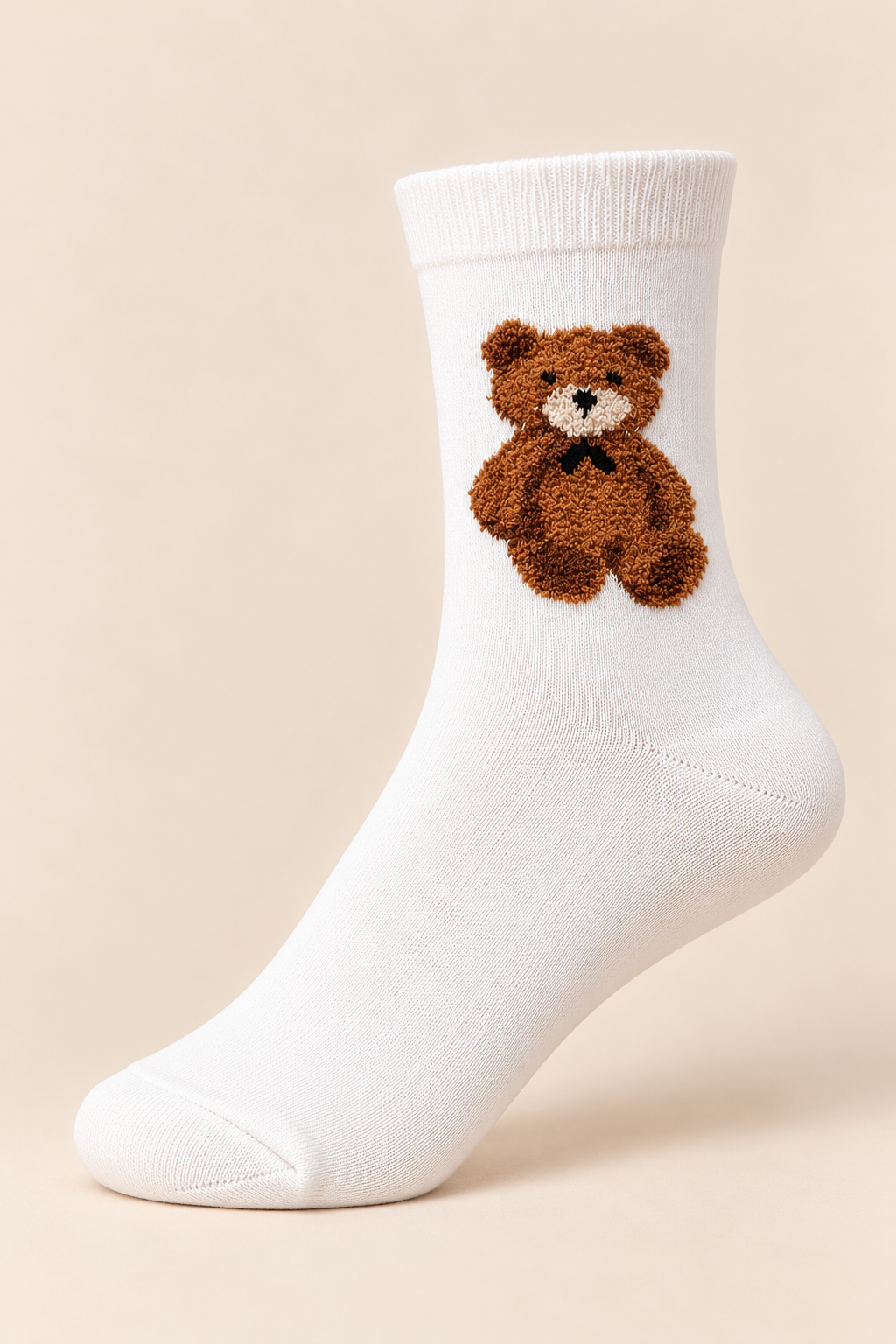 Witte damessok met bruine teddybeerprint en zwart strikje op een beige achtergrond.